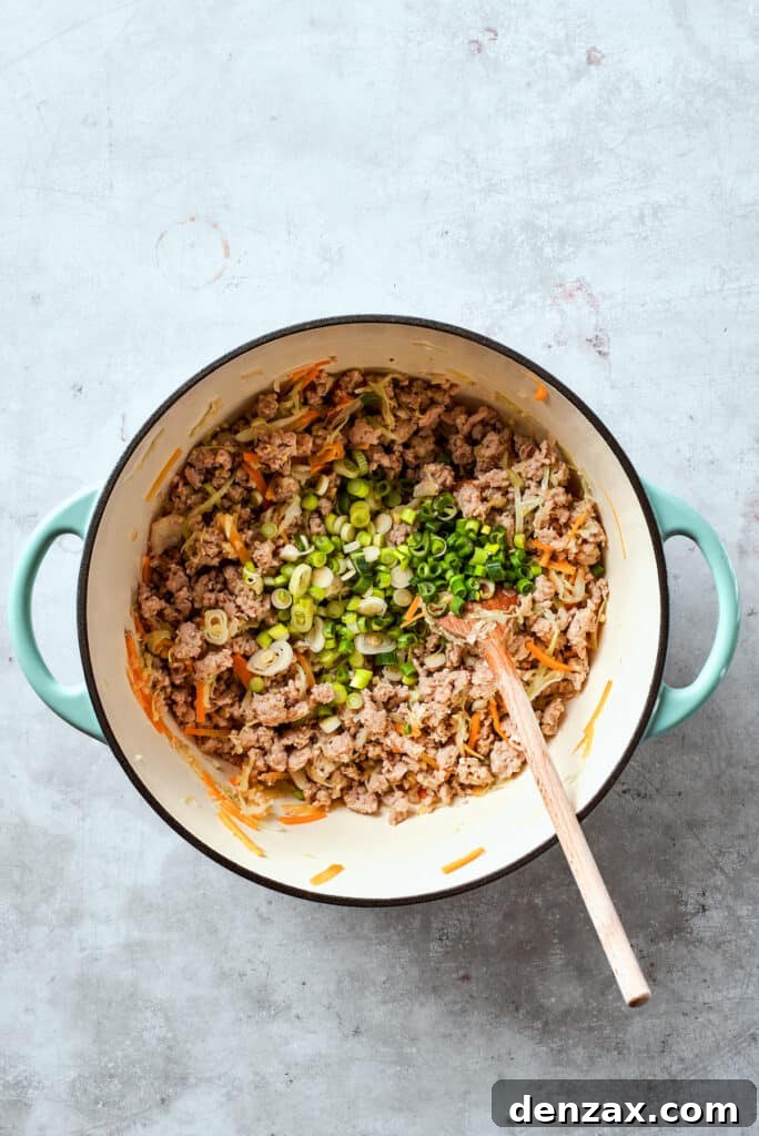 Bright green sliced green onions are stirred into the rich, savory chicken and vegetable filling, adding a fresh, aromatic finish to the mixture for the egg rolls.