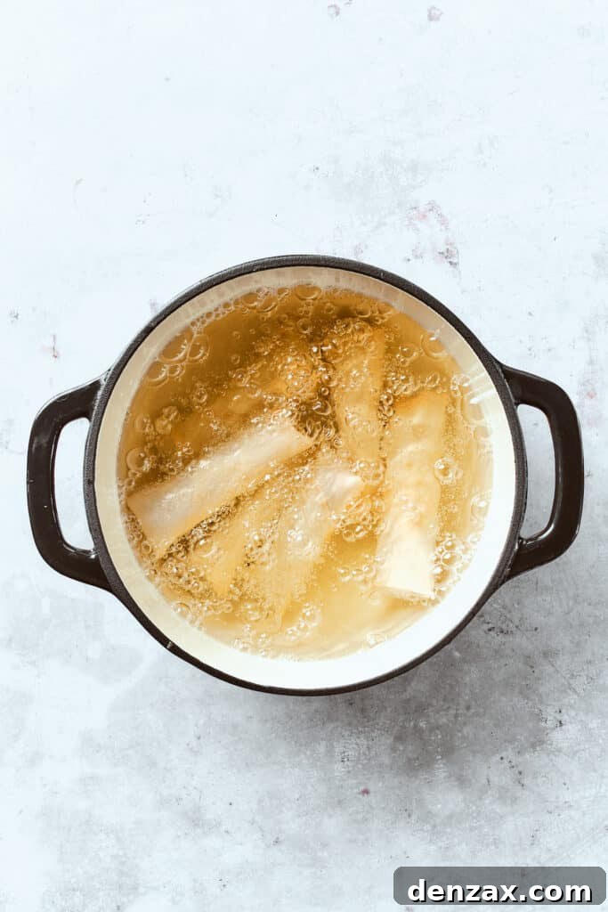 Several chicken egg rolls are submerged in a bubbling pot of hot oil, frying to a beautiful golden brown, promising a deliciously crispy texture.