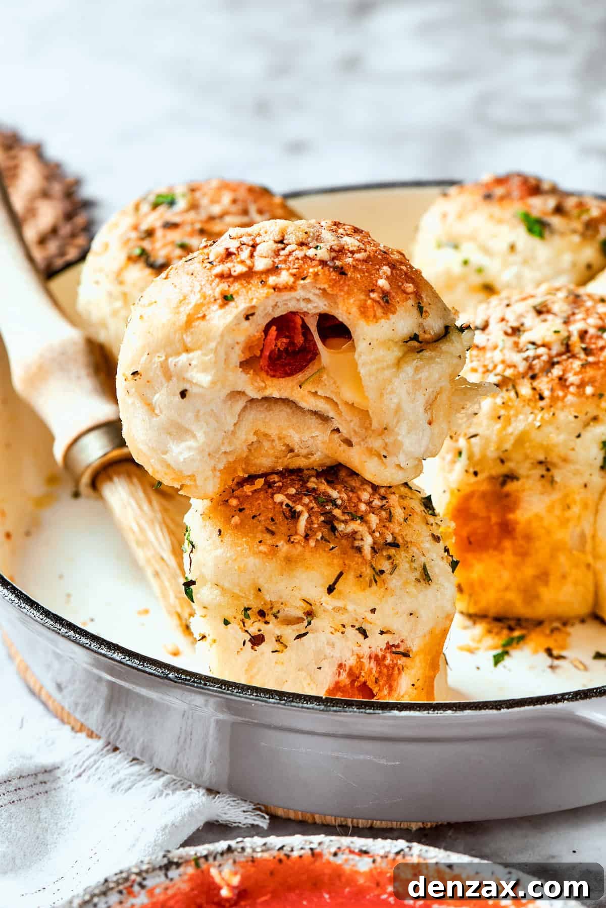 A serving utensil gently lifts a golden-brown, cheesy pizza bite from a skillet, showcasing its perfectly crisp exterior.
