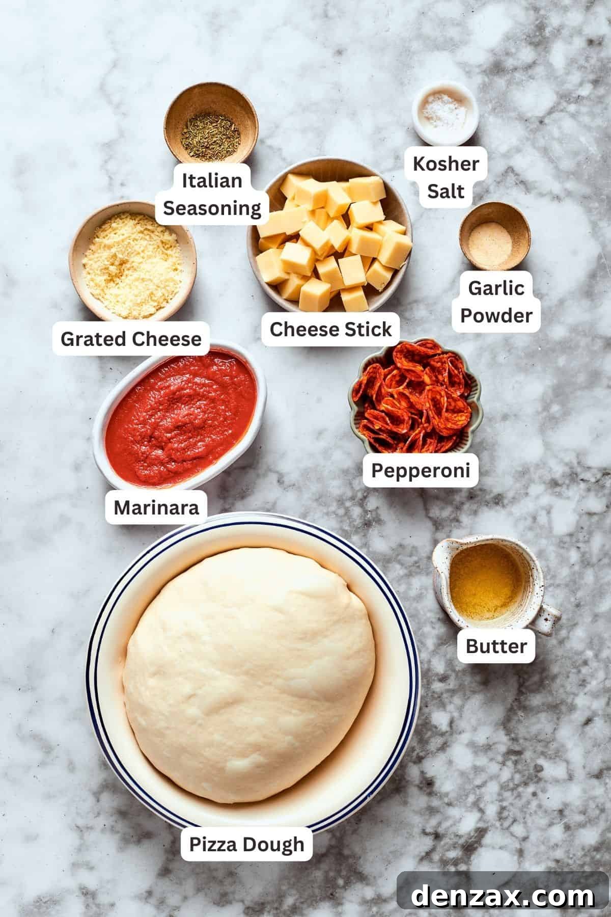 Various ingredients for pizza bites are neatly arranged and labeled on a cutting board, including pizza dough, shredded cheese, Italian seasoning, marinara sauce, sliced pepperoni, melted butter, garlic powder, a cheese stick, and salt.