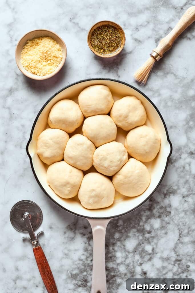 Twelve prepared pizza bites, neatly sealed and arranged in a greased skillet, ready for the herbed butter and cheese.
