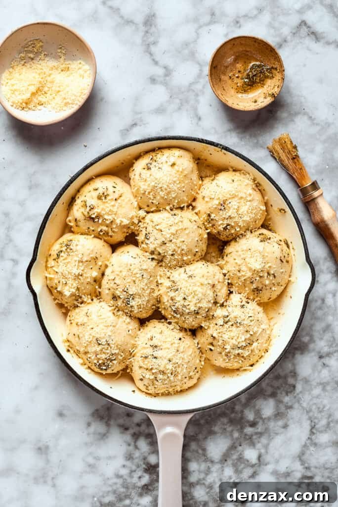 The skillet of pizza bites, now brushed with herbed butter and sprinkled with Parmesan, perfectly prepped for baking.
