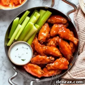 A view of a table holding a towel and a pan with buffalo wings, sauce, and celery.