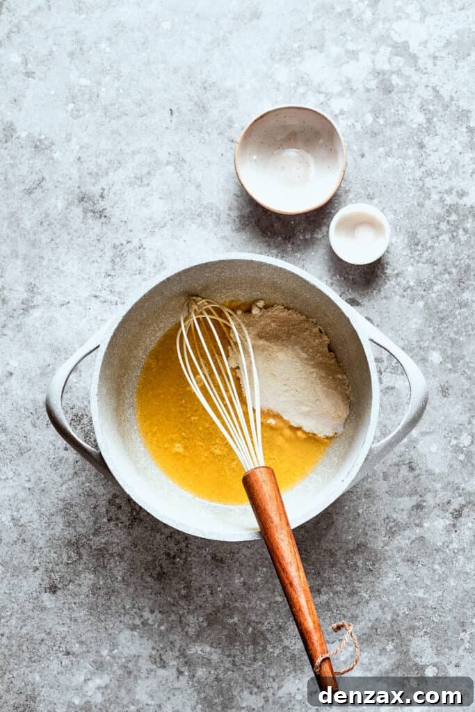 Flour being whisked into melted butter in a saucepan to create a roux for the gravy.