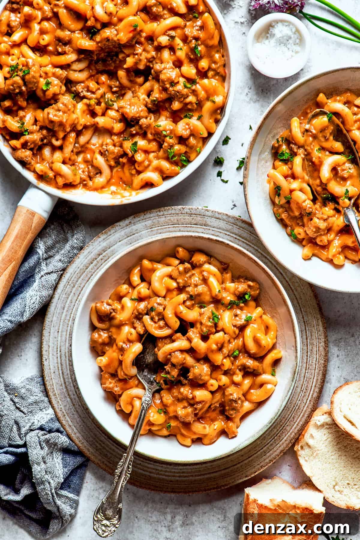 Bowls of homemade hamburger helper, with a spoon revealing the rich, cheesy pasta and ground beef mixture.