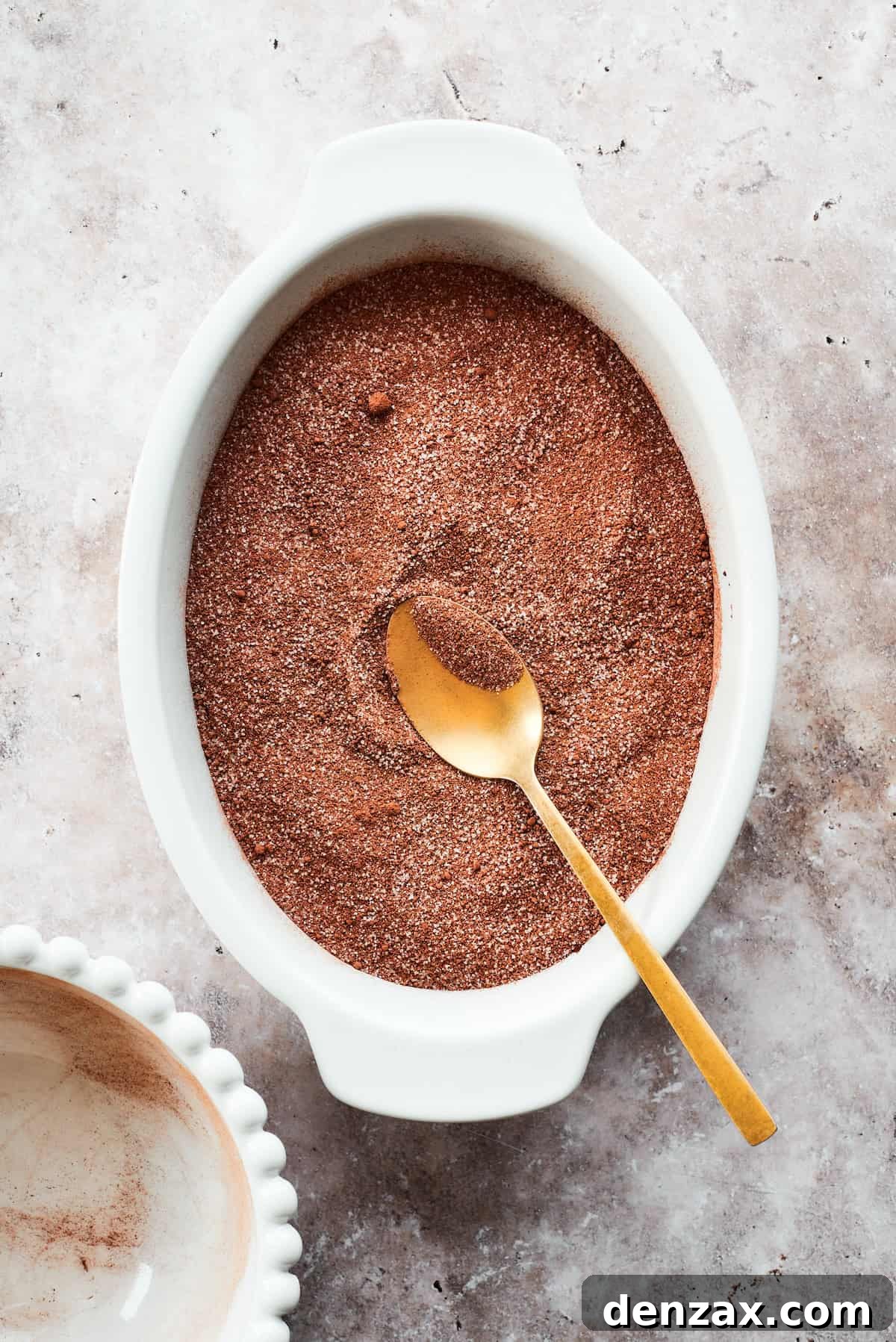 The dry fudge topping mixture is evenly spread over the chocolate cake batter in the baking dish, creating a uniform layer.