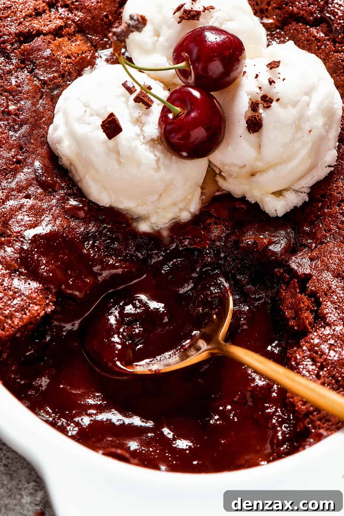 A close-up shot of a golden spoon stirring through the rich, gooey layers of a warm chocolate pudding cake, highlighting its decadent texture.
