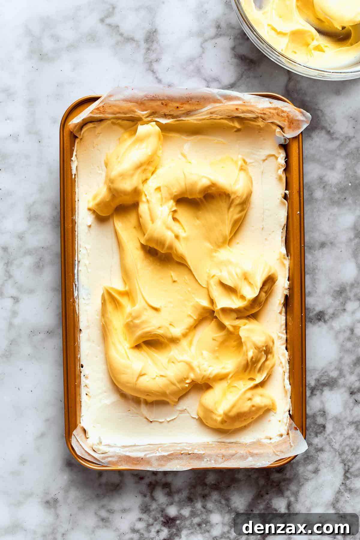 The thickened vanilla pudding is gently spread over the cream cheese layer in the baking dish, creating the next distinct layer of the dessert.