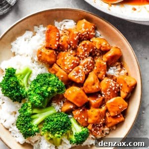 Teriyaki chicken pieces served over rice in a bowl with a side of broccoli.