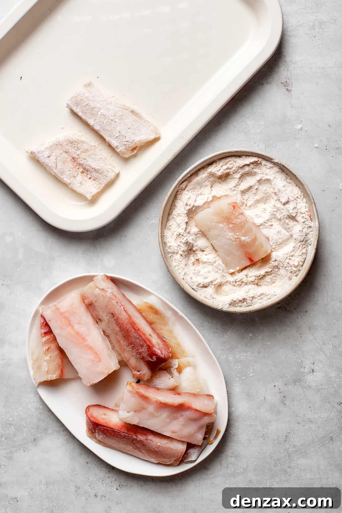A piece of white cod is being dredged in a seasoned flour mixture.