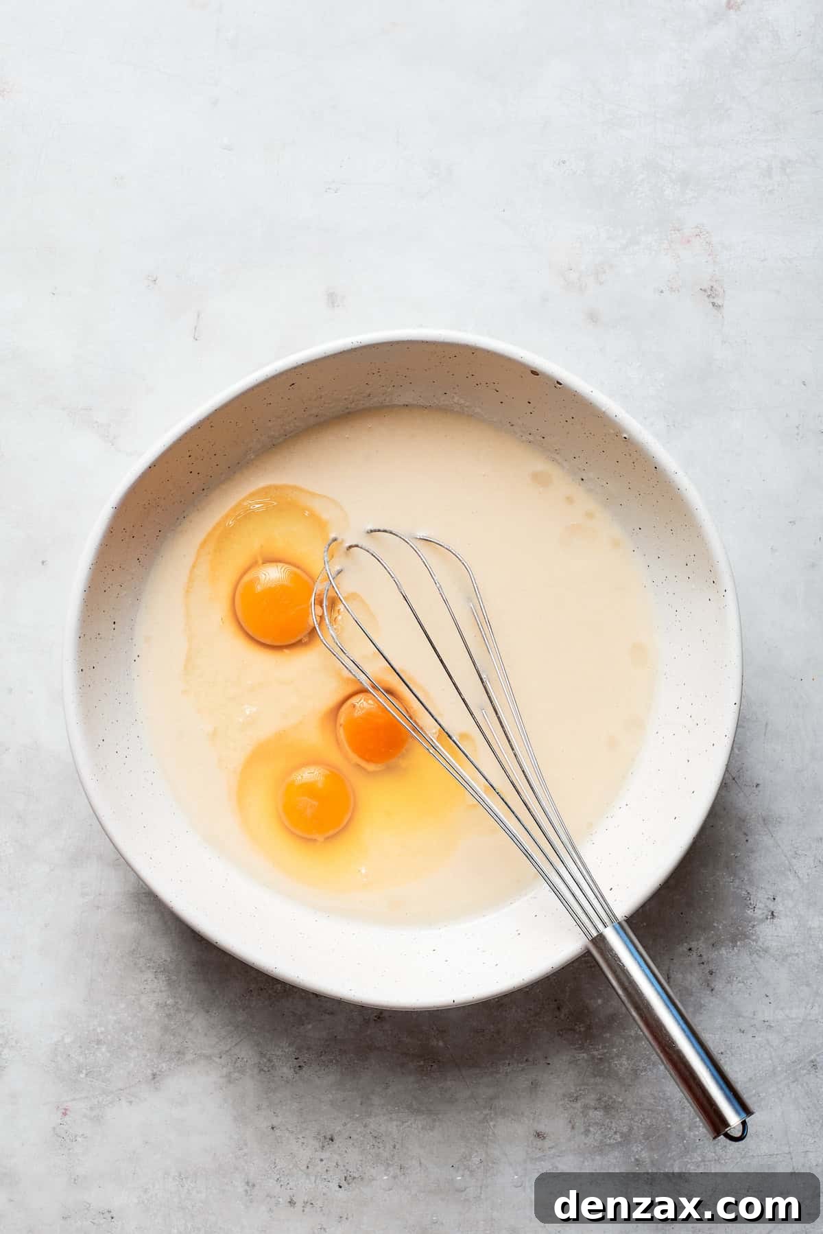 Large eggs are carefully cracked and added to the batter of Amish friendship bread.