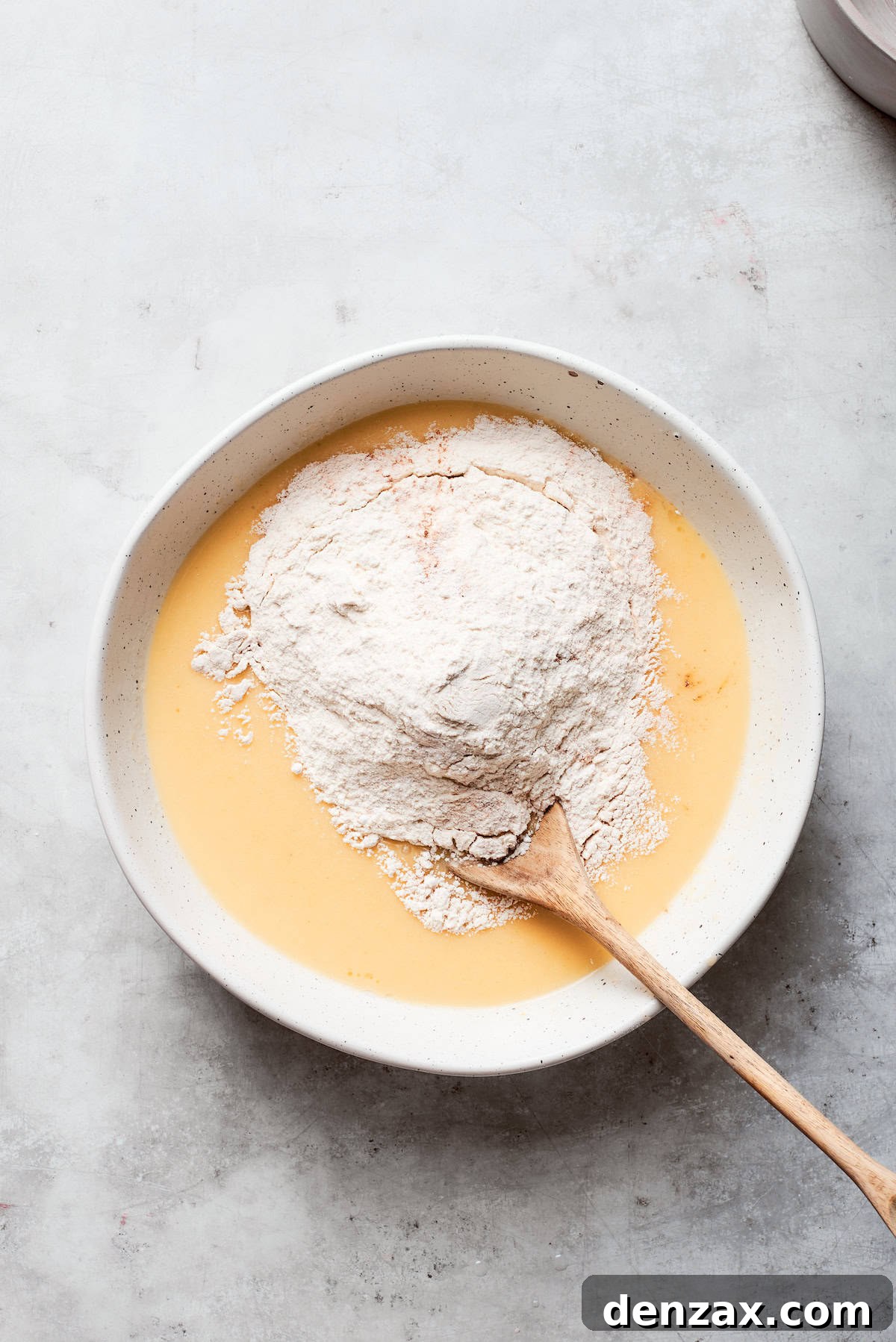 All-purpose flour is gently stirred into the wet batter until just combined.