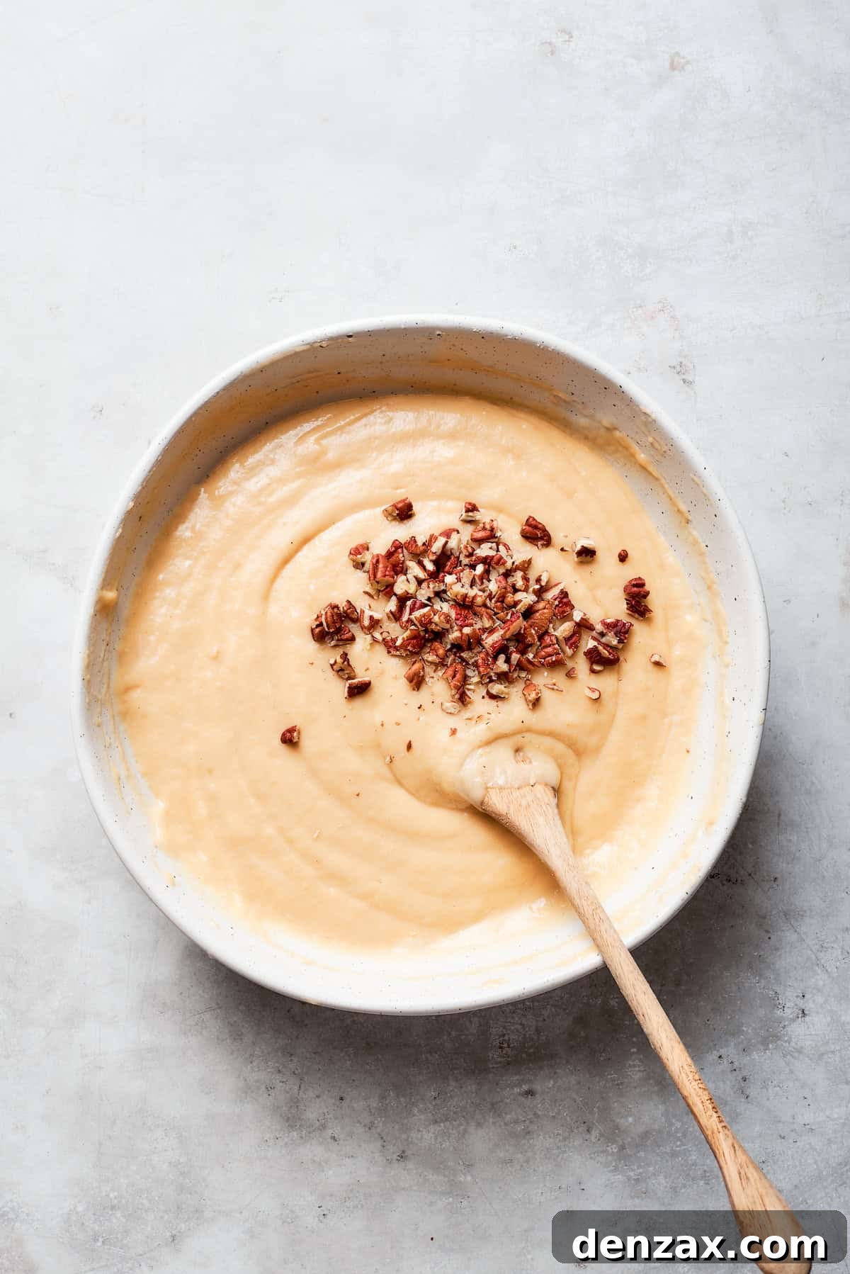 Chopped pecans are gently folded into the smooth bread batter, ensuring even distribution.