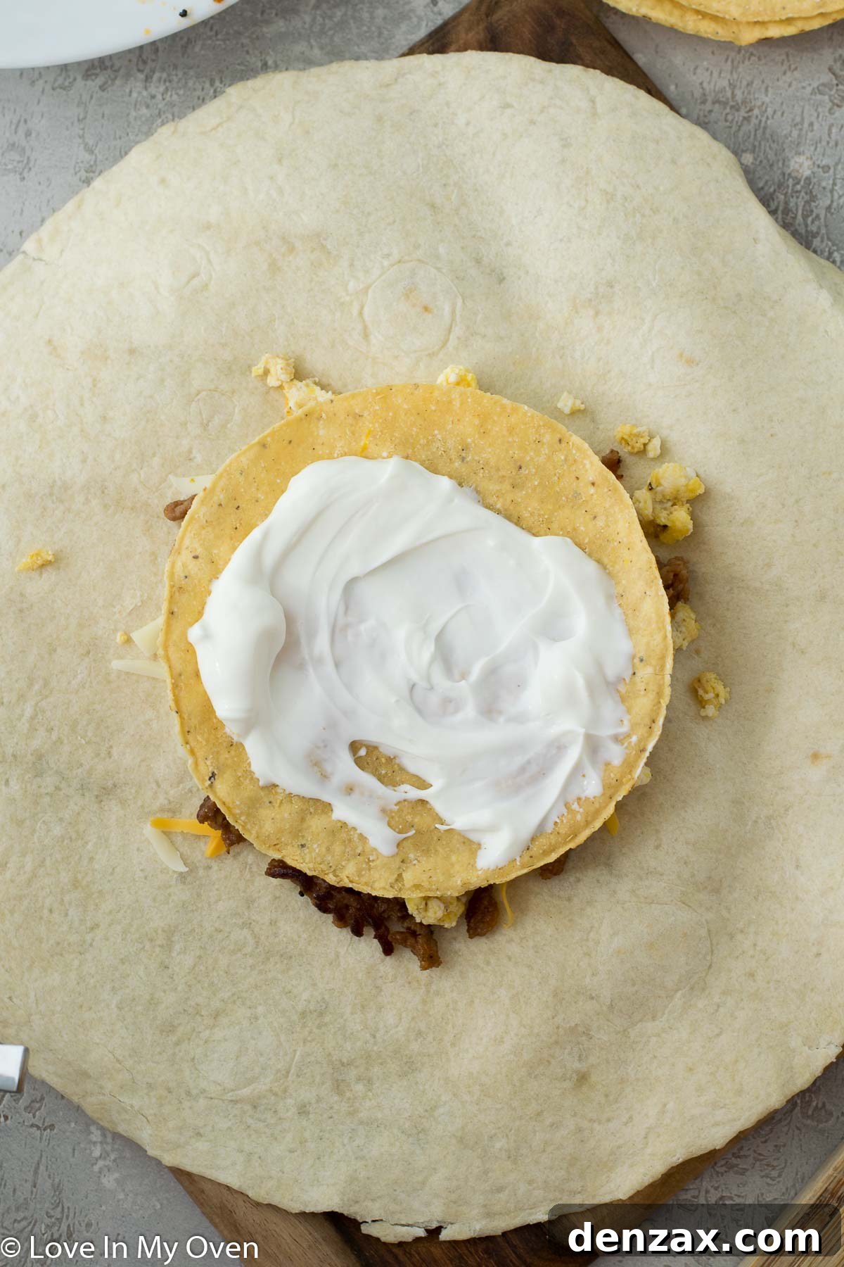 Layering cheese and chorizo on a tortilla for a crunch wrap.