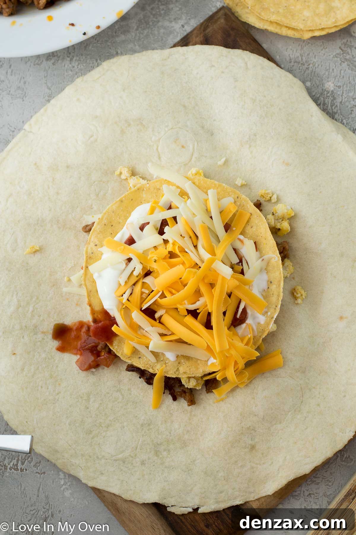 Adding scrambled eggs to the breakfast crunch wrap layers.