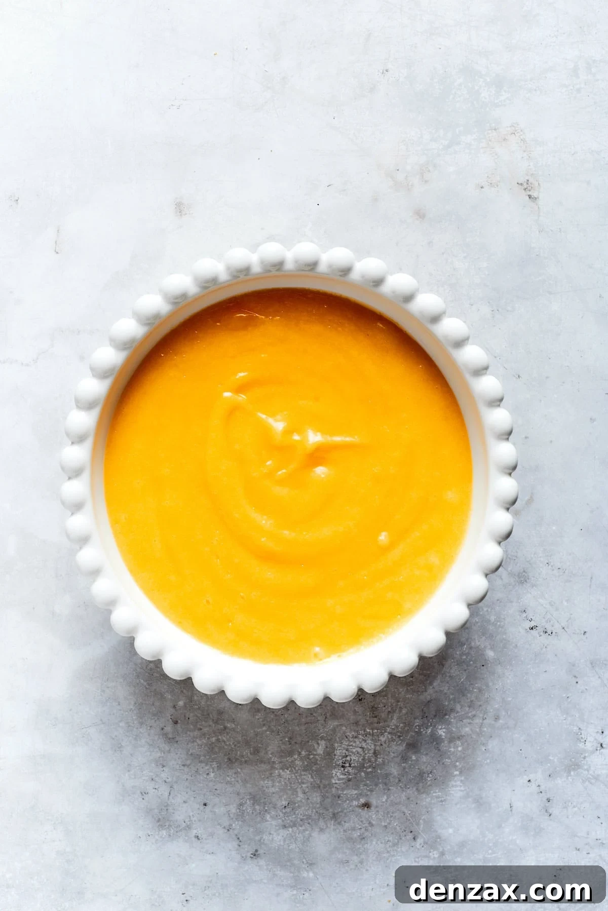 A bowl of freshly made, golden lemon curd, perfectly smooth and glistening, indicating proper thickness.