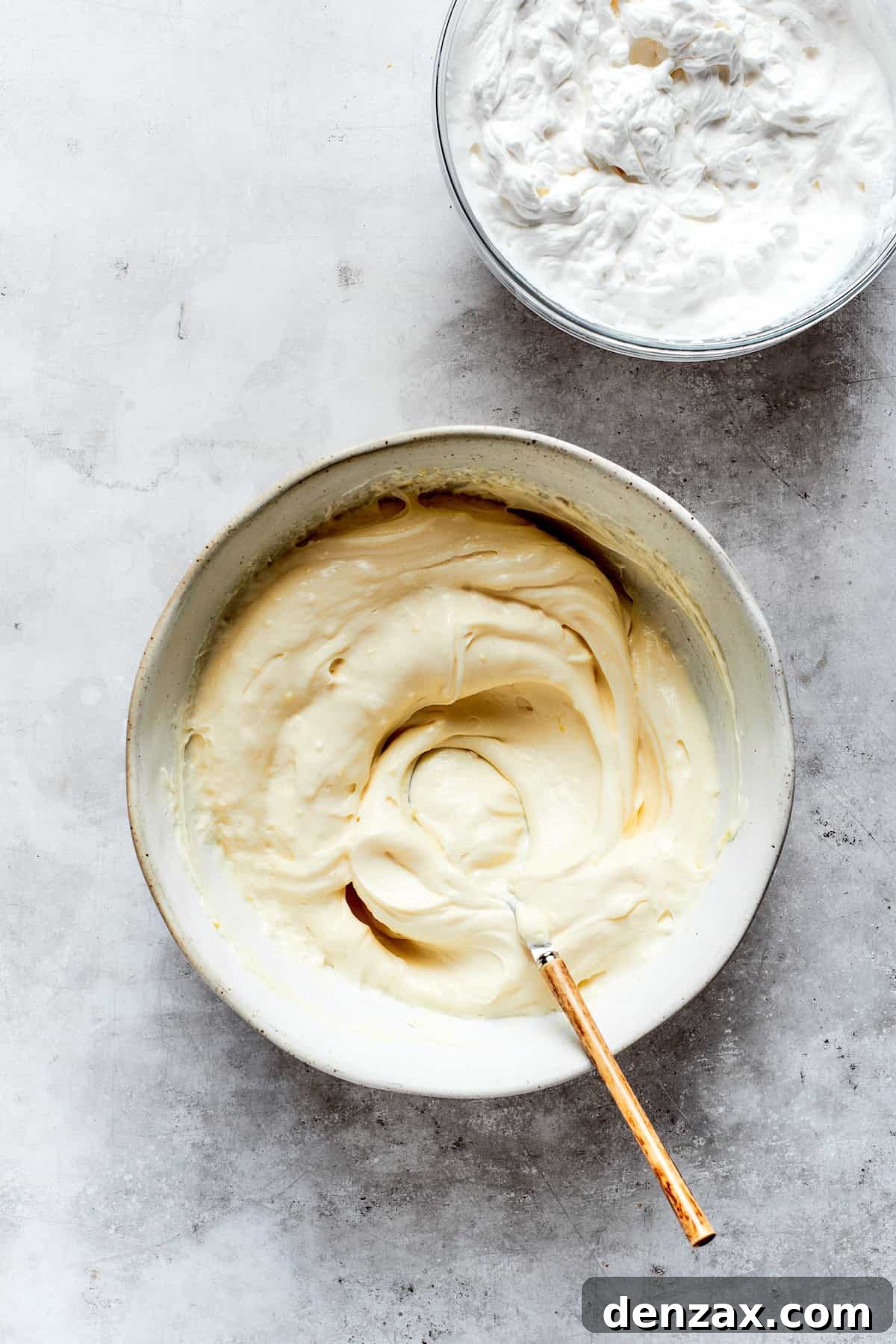 Mascarpone cheese, sugar, vanilla, and lemon zest are being mixed together in a bowl until smooth and well-combined for the creamy filling.