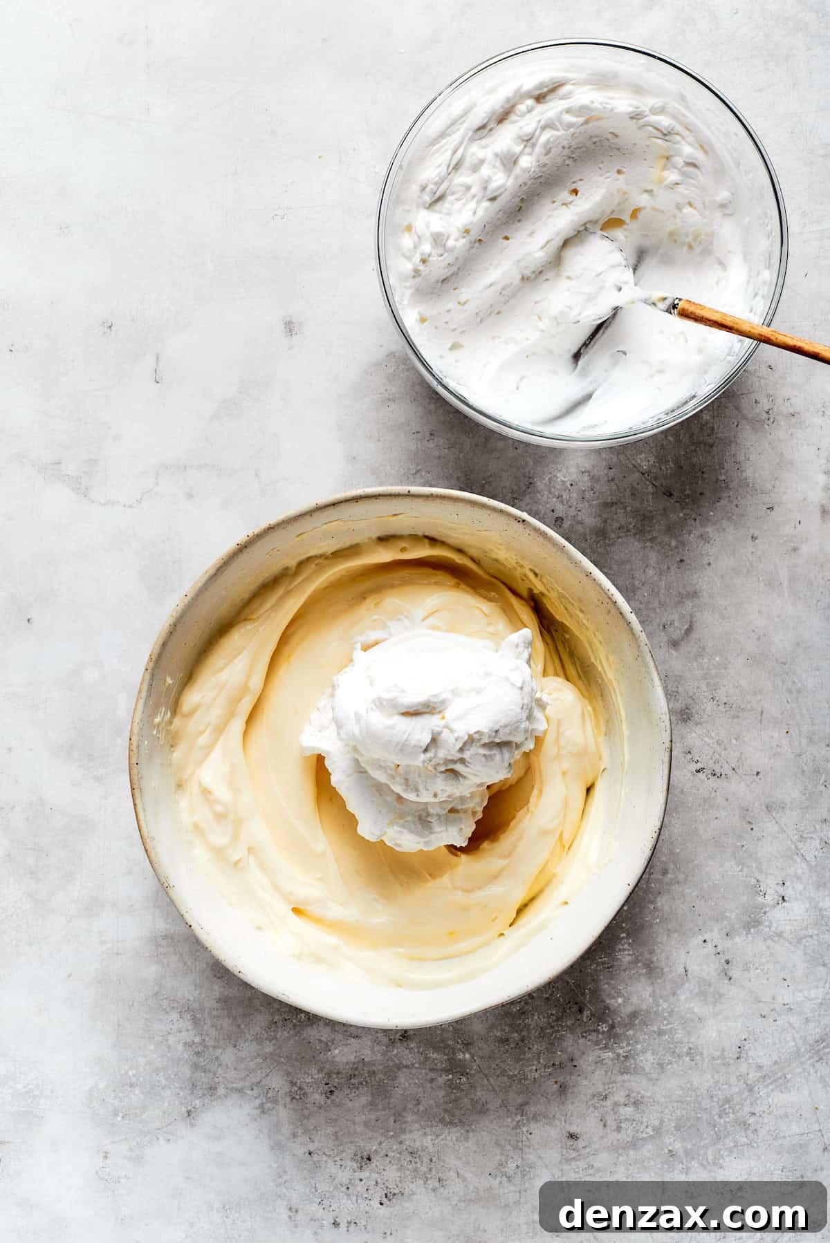 Light and fluffy whipped cream is being gently folded into the mascarpone mixture, creating an airy and smooth tiramisu filling.