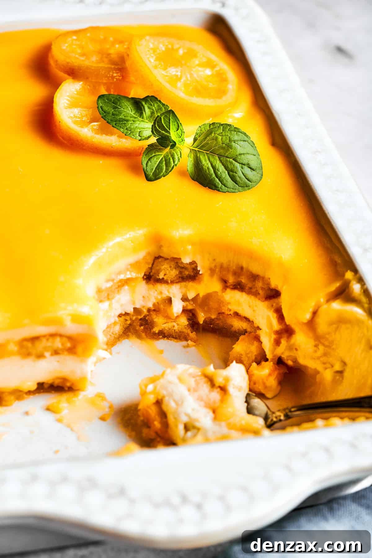 Half of a pan of lemon tiramisu, with several luscious pieces already cut out and served, revealing the beautiful layers within.