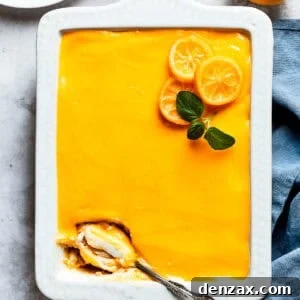 A serving spoon is digging into the corner of a pan of lemon tiramisu, revealing its luscious layers.