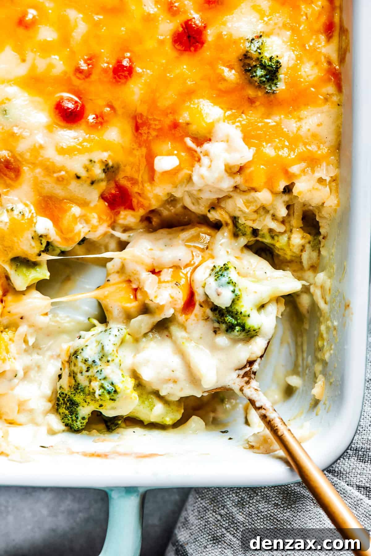 A serving spoon scooping out broccoli rice casserole from a baking dish.