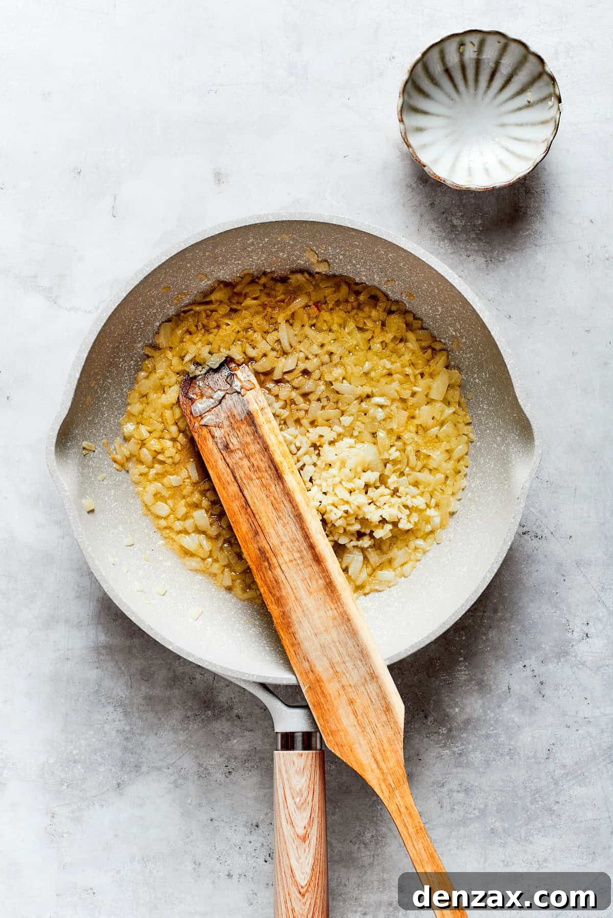 Garlic and onion are stirred in a pot.