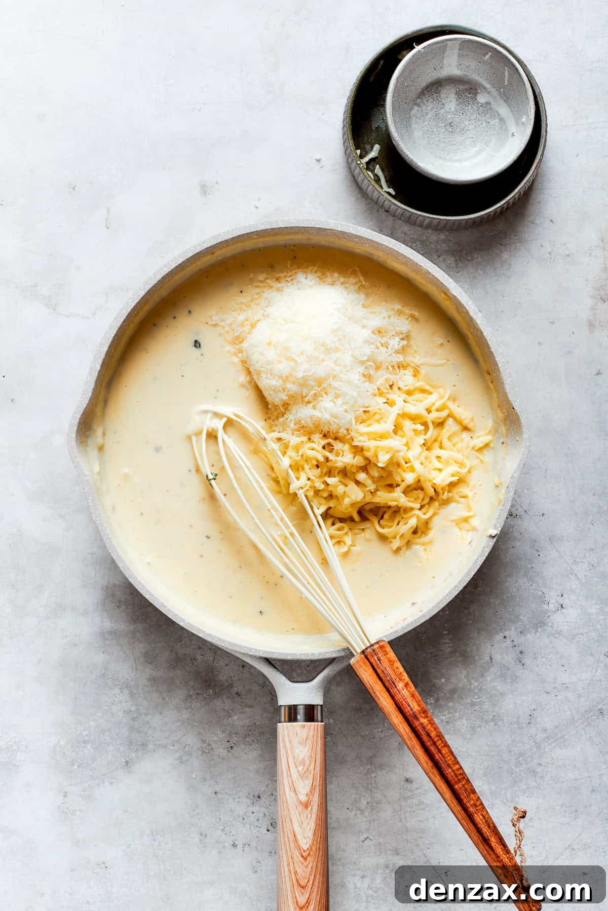 Cheeses are added to a roux in a pot.