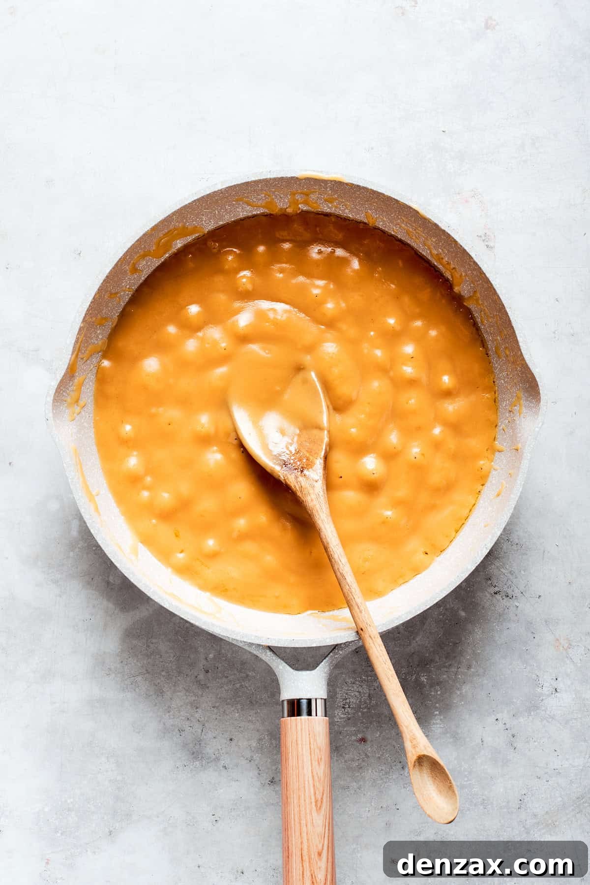 Caramel sauce is stirred until smooth and beginning to thicken in a pot.