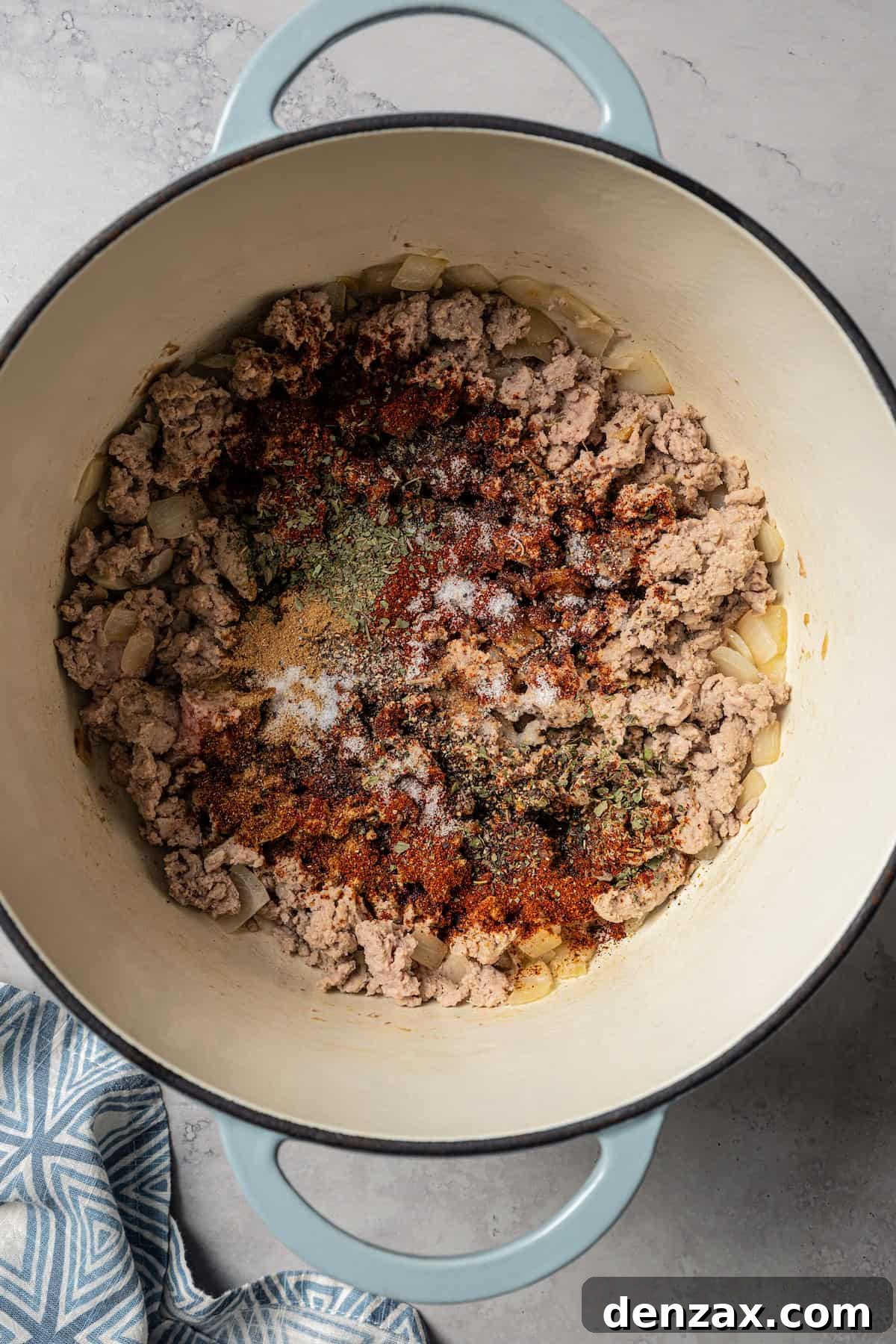 Seasoning added to browned ground turkey in a large pot.