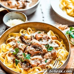 Bowl of chicken and mushrooms served on top of noodles.