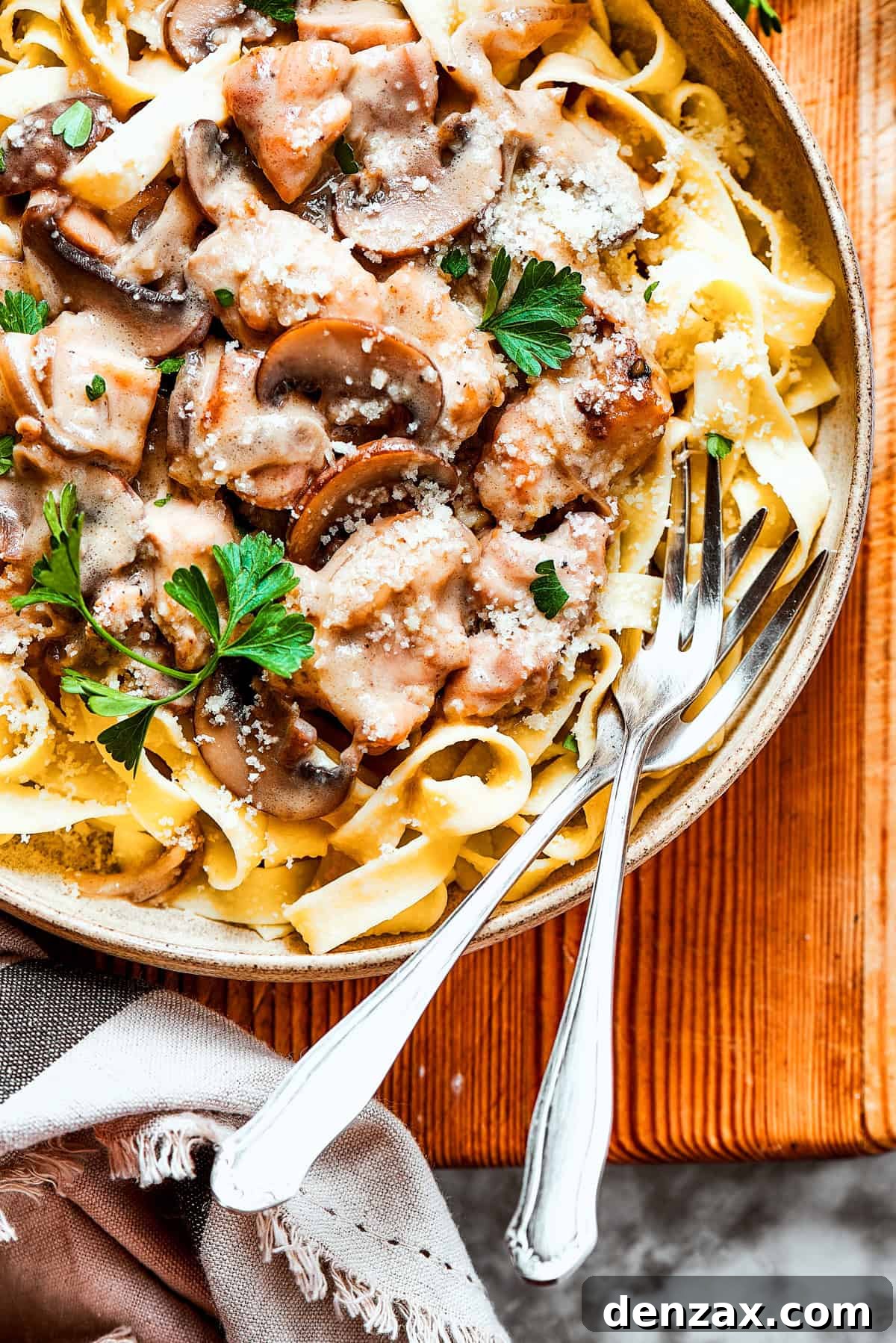 A bowl of chicken marsala noodles with two forks resting inside the bowl.