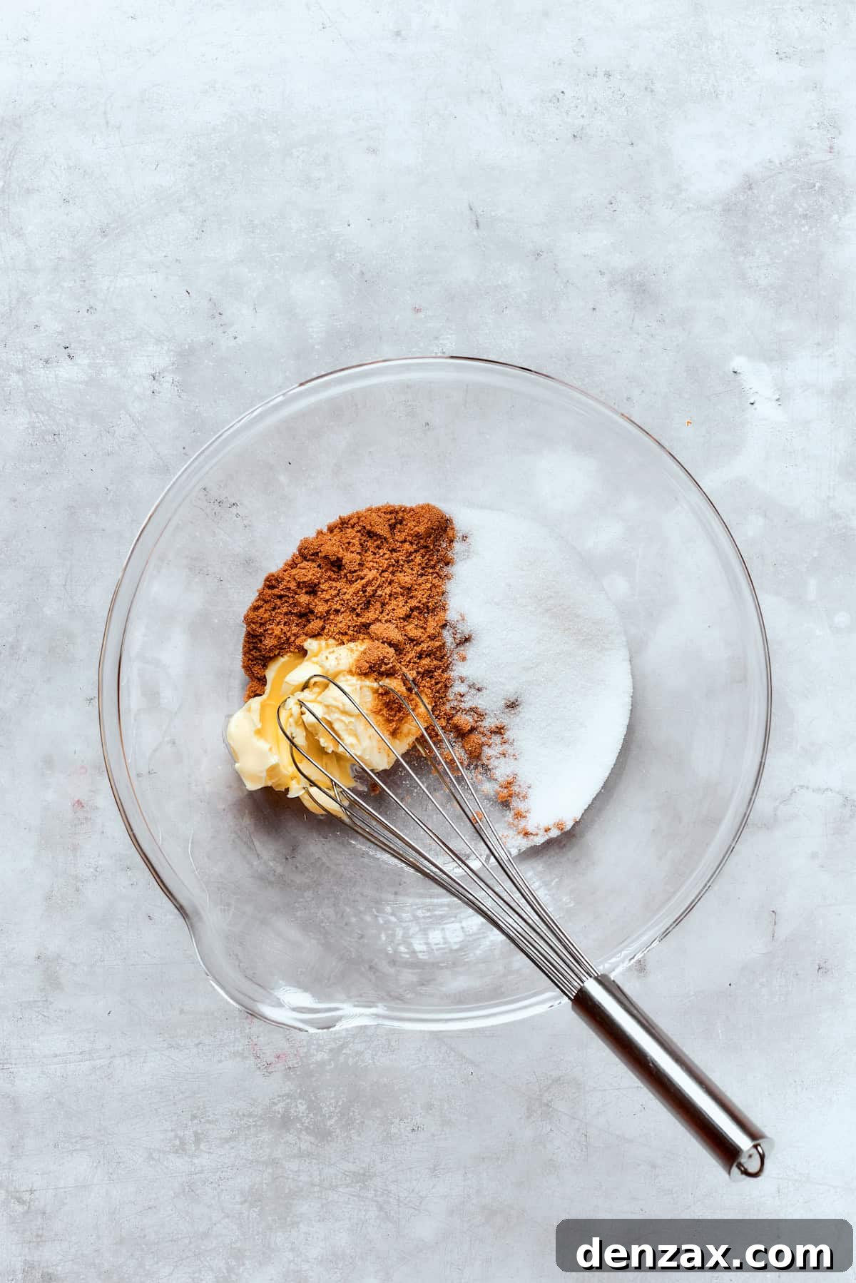 Softened butter being creamed together with granulated and brown sugar in a large mixing bowl, creating a light and fluffy base.