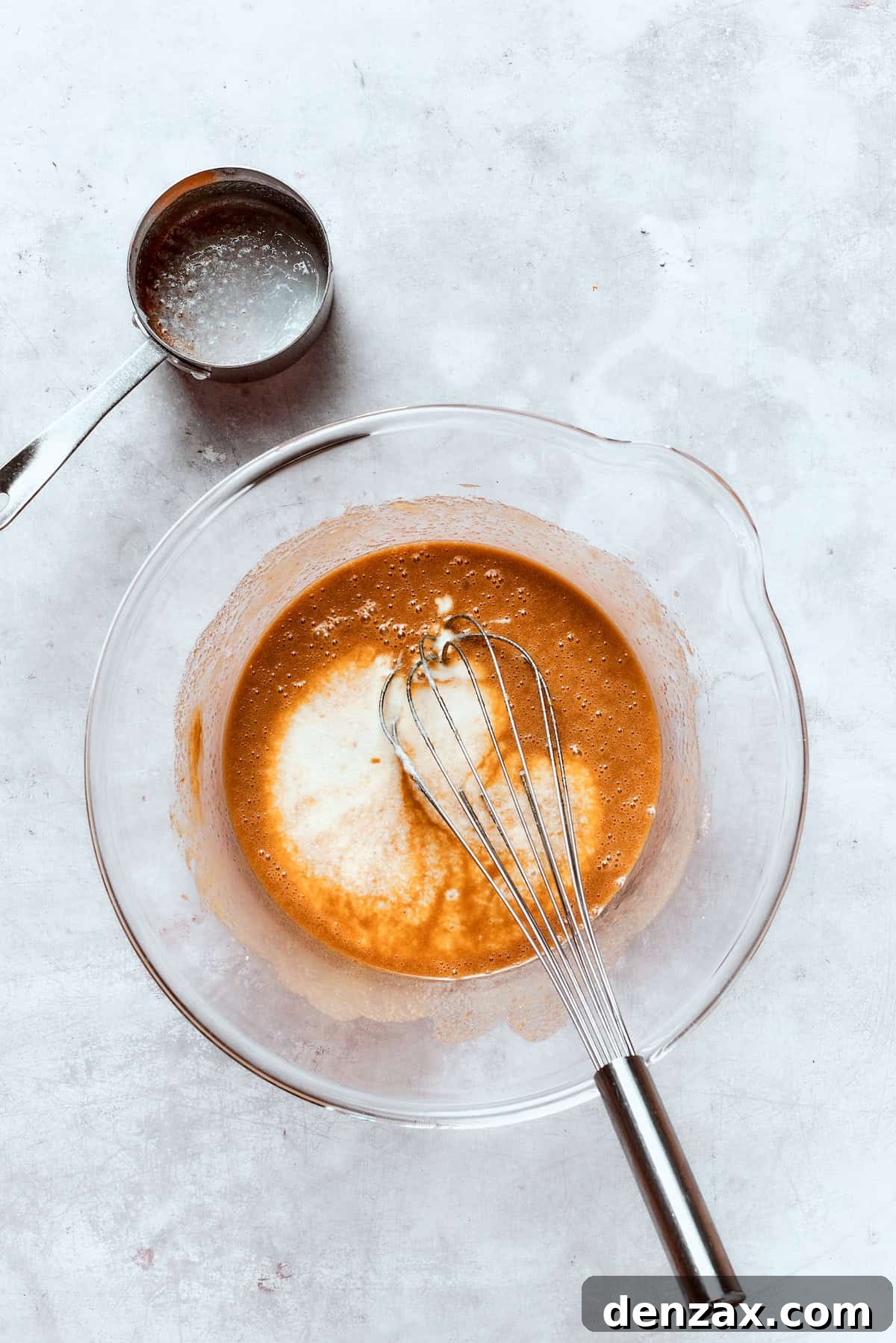 Buttermilk being gently whisked into the donut batter, adding crucial tang and moisture for a tender crumb.