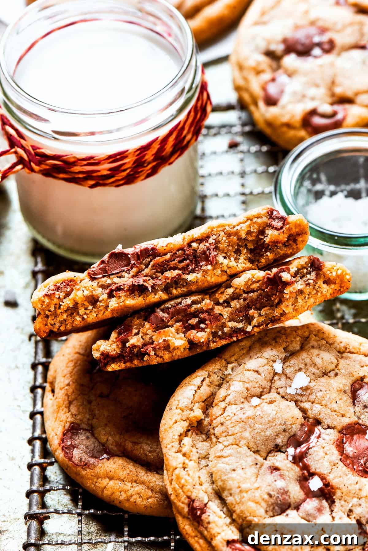 Freshly baked brown butter chocolate chip cookies cooling on a rack, with a vintage jug of milk in the background, suggesting a perfect pairing.