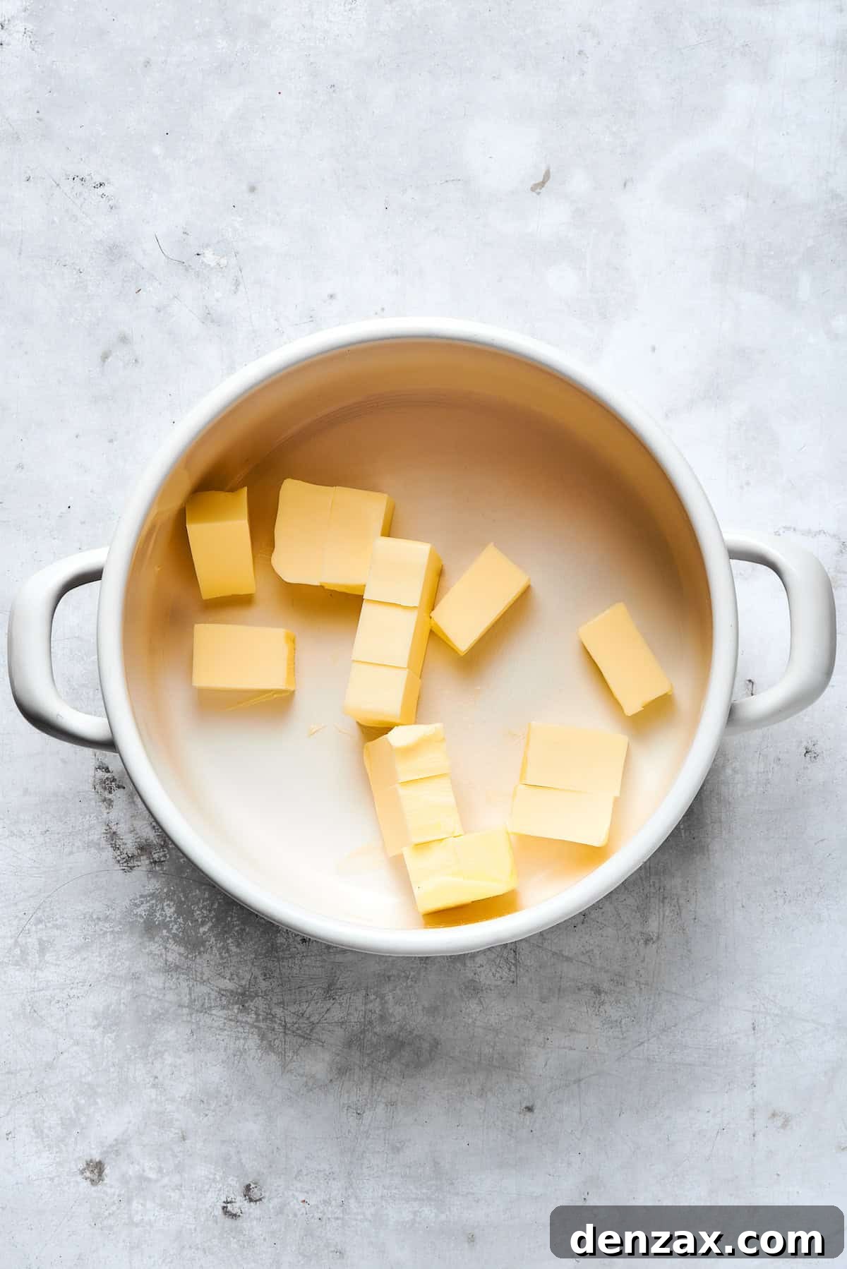 Pieces of unsalted butter melting in a medium saucepan over gentle heat.