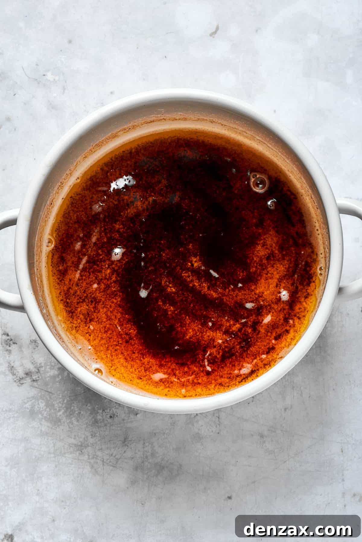 A pot of rich, dark golden-brown browned butter with toasted milk solids at the bottom, radiating a nutty aroma.