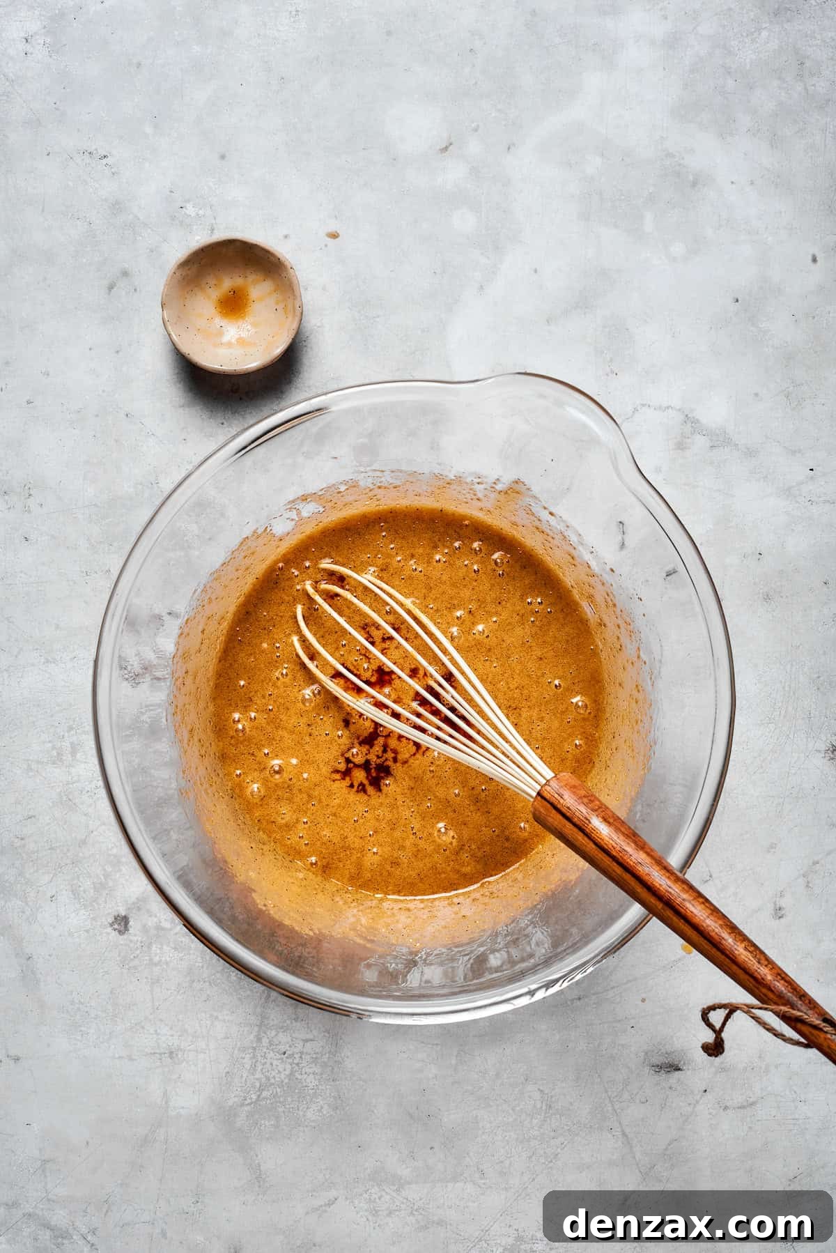 The wet cookie dough mixture, including browned butter, sugars, and eggs, being thoroughly whisked until light and cohesive.