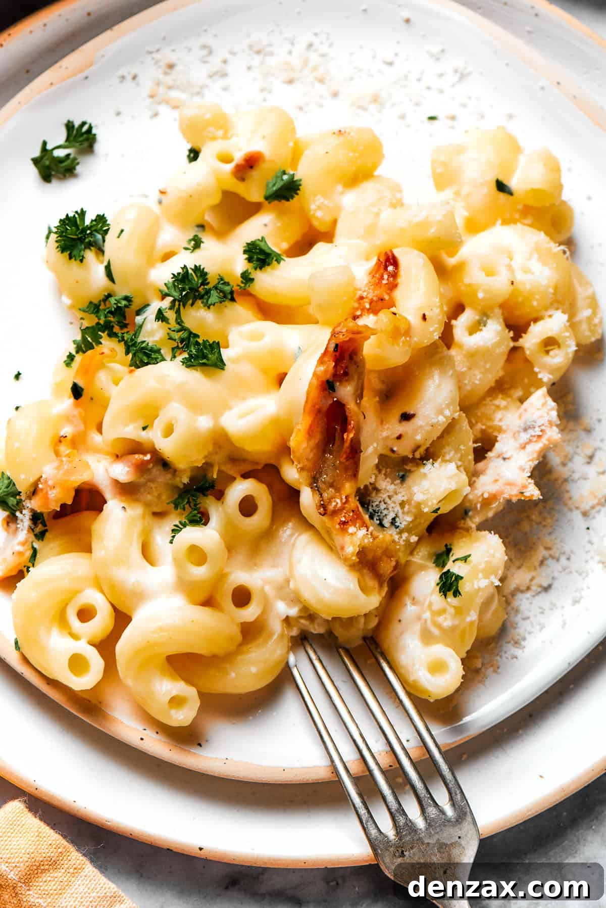 A generous serving of creamy garlic parmesan chicken pasta on a white dinner plate, garnished with fresh parsley.