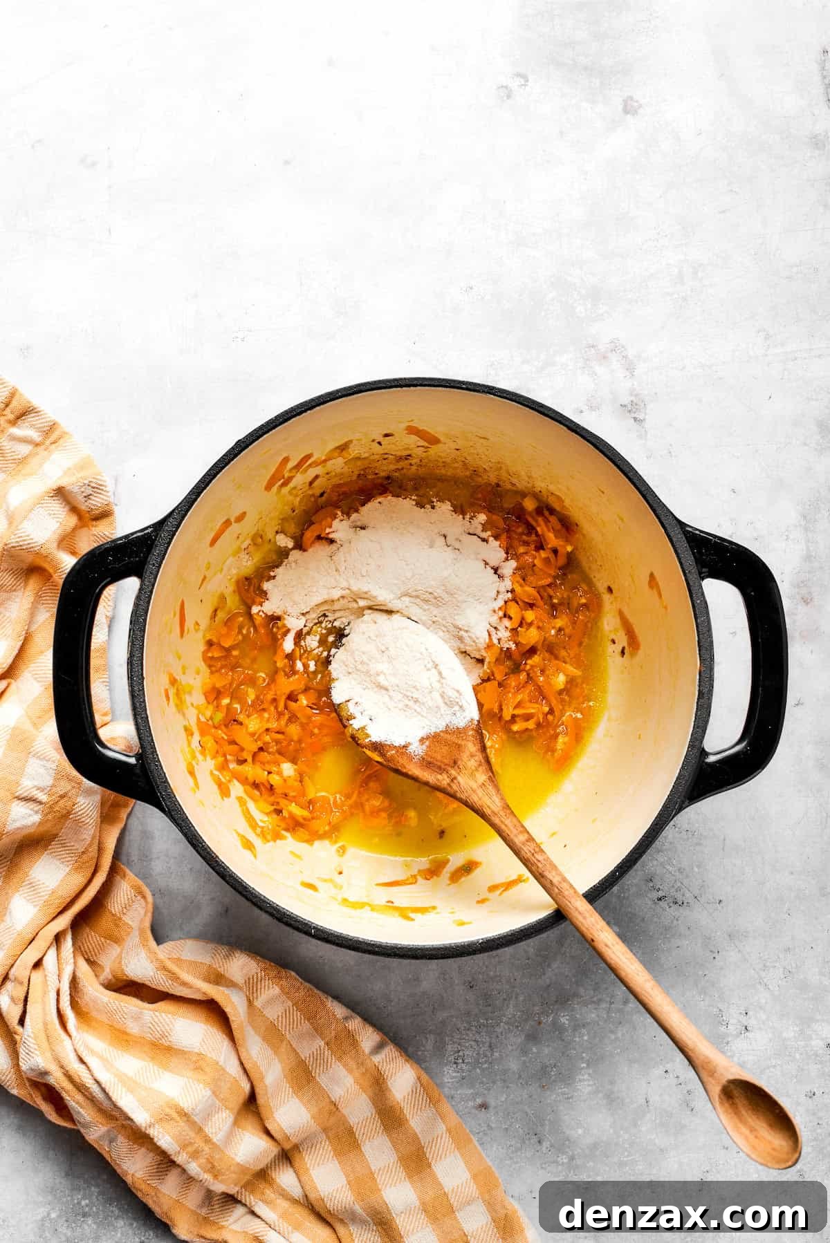 Sprinkling all-purpose flour over the melted butter and cooked vegetables to form the thickening roux.