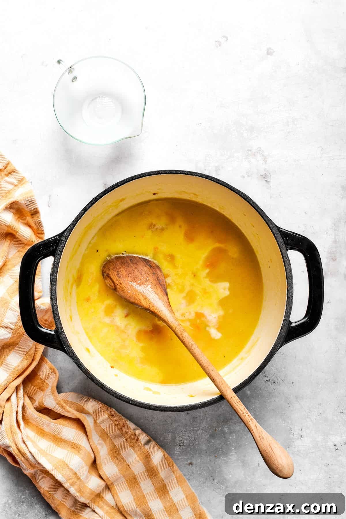 Stirring fresh milk into the soup base to enhance its creamy texture and flavor.