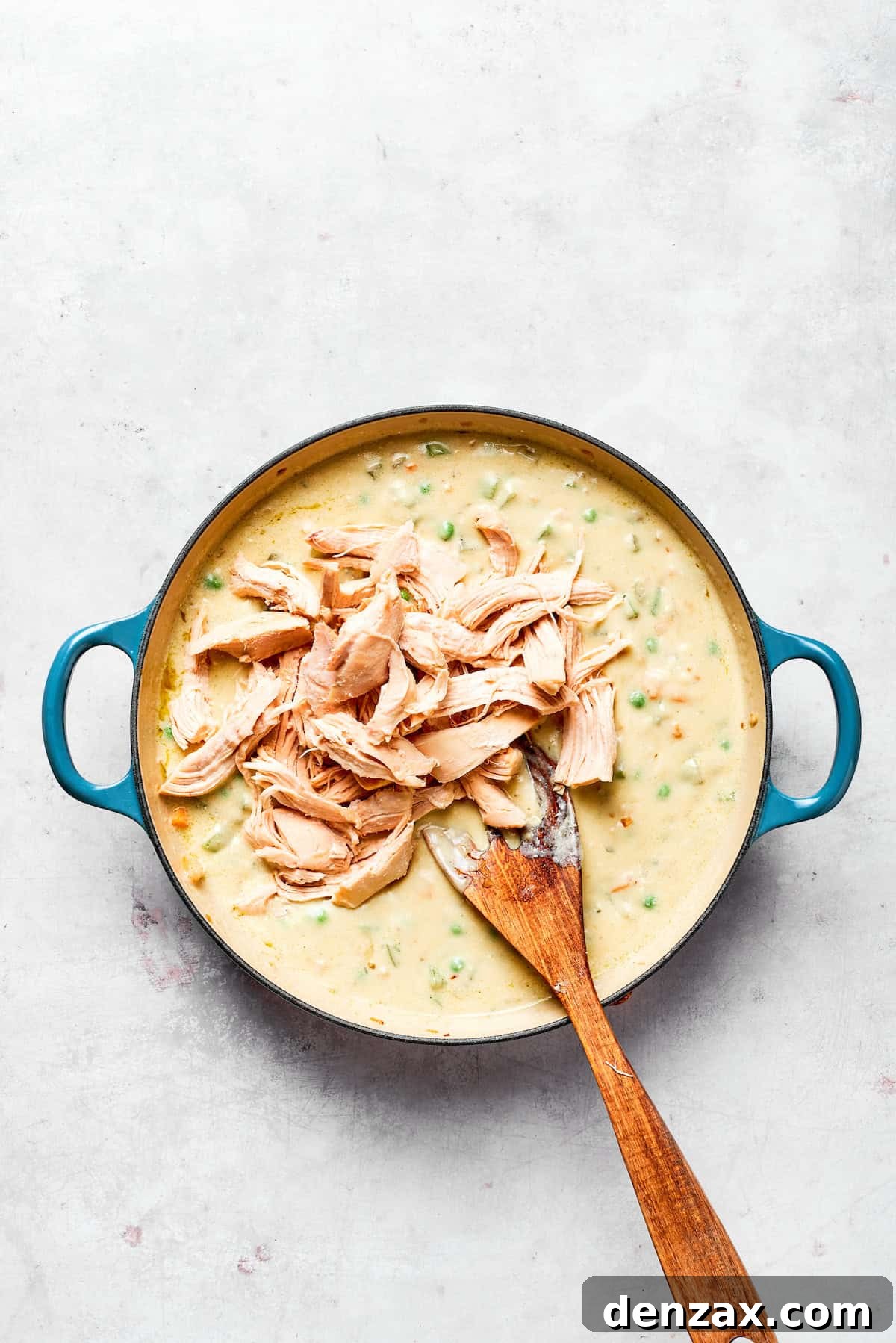 Mixing in the shredded chicken with the creamy vegetable mixture.