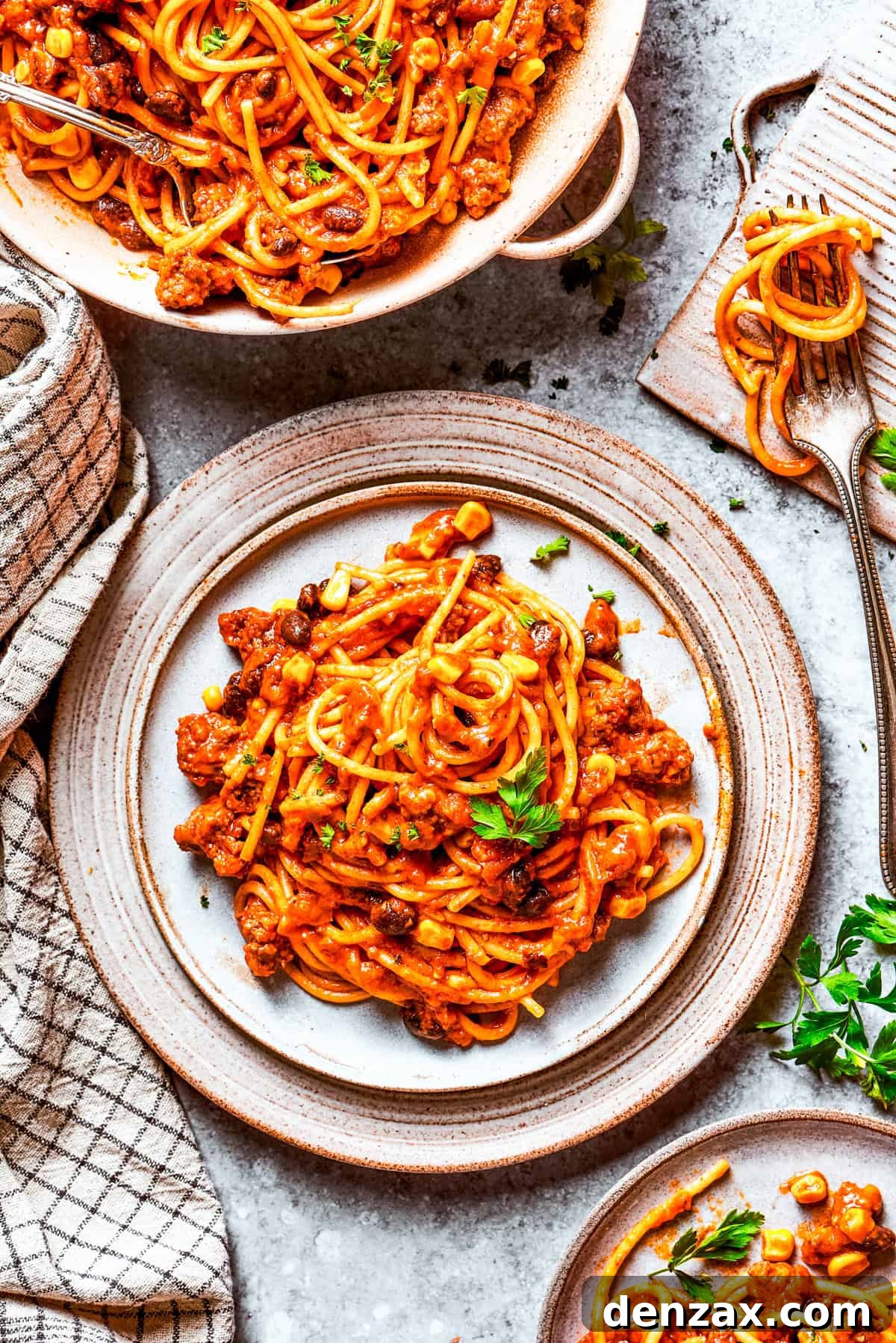Two plates of Mexican spaghetti, garnished with fresh cilantro and a dollop of sour cream or crema, ready to be served for a family dinner.