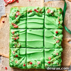 A green Grinch cake is precisely cut into 12 pieces, showcasing its even frosting and decorations.