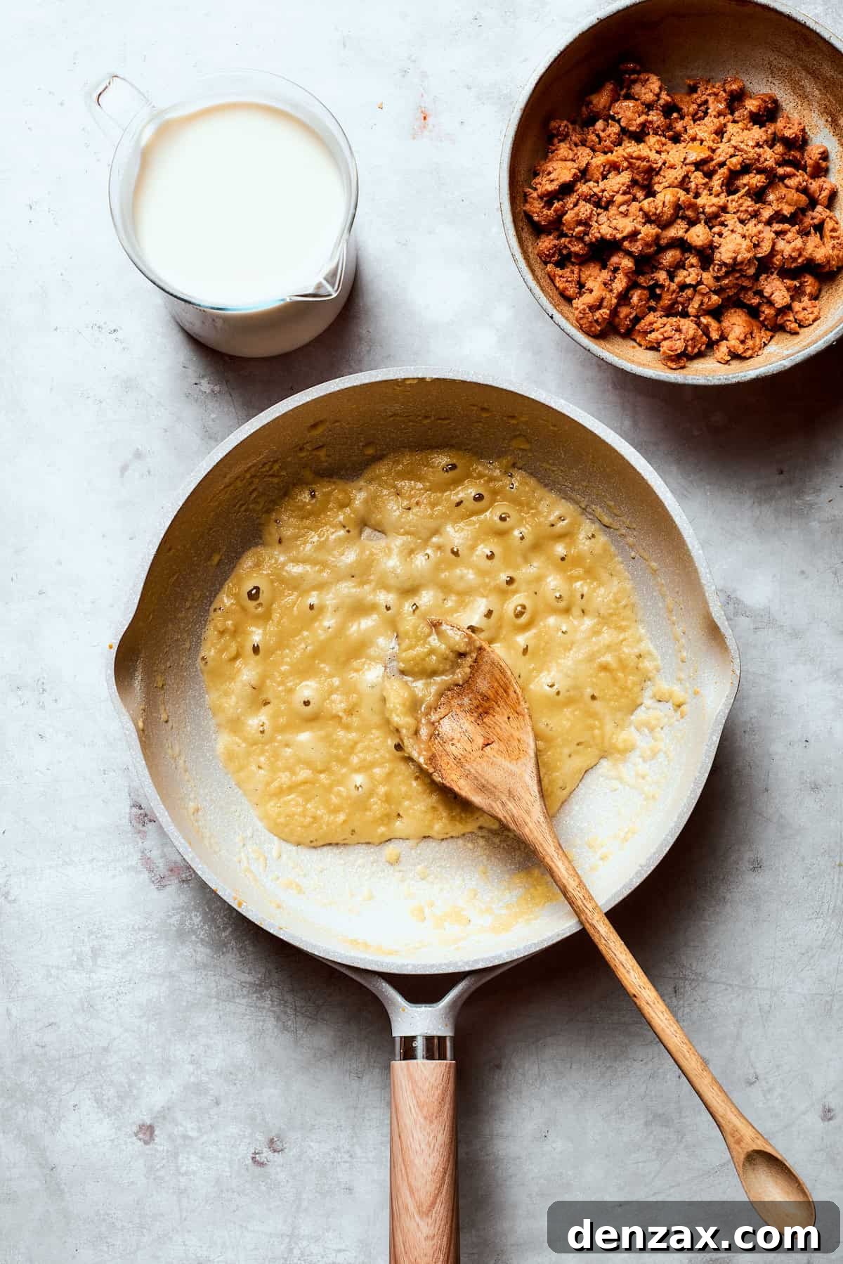 A roux being stirred consistently in a skillet, turning lightly golden.