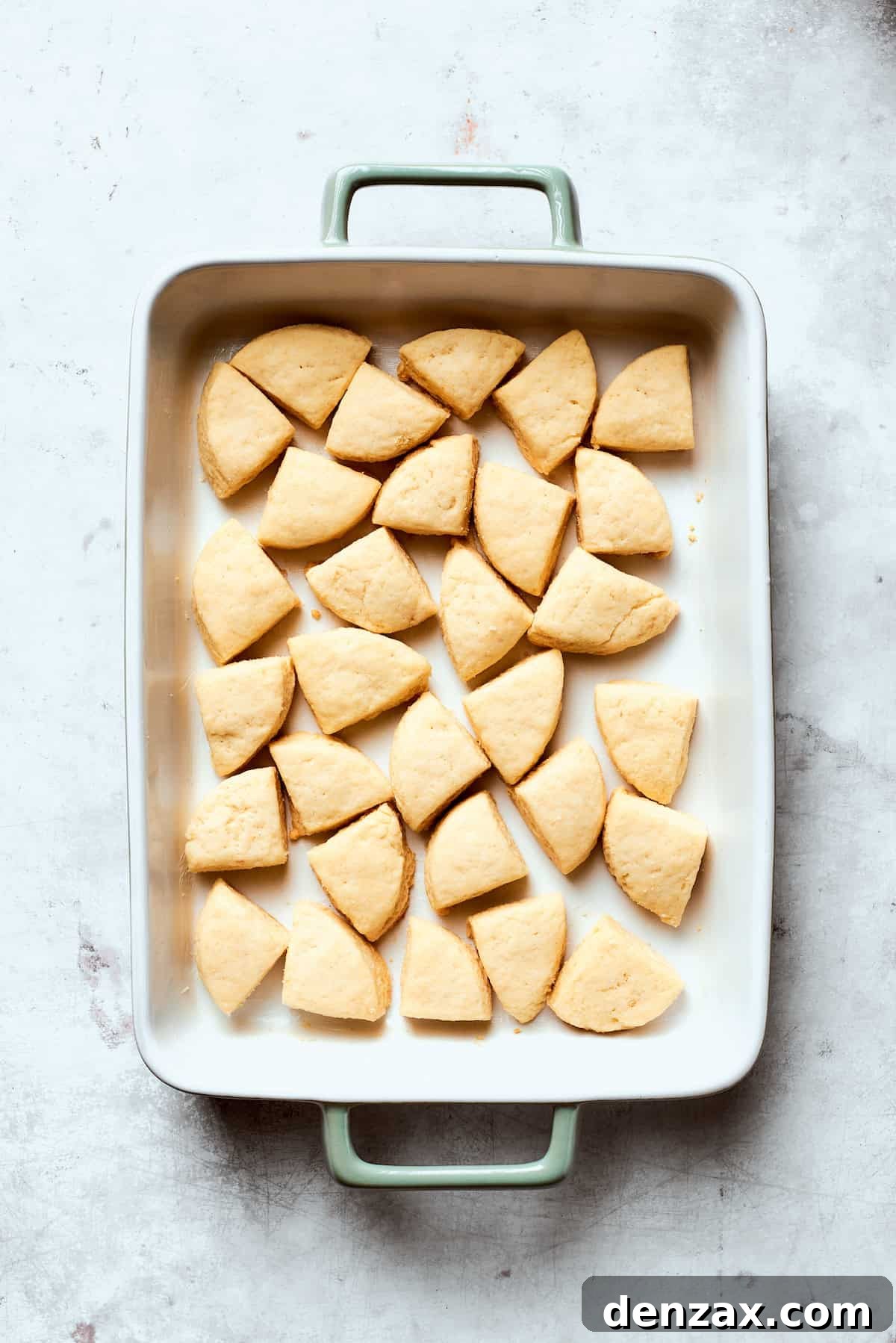 Quartered pieces of refrigerated biscuit dough arranged evenly across the bottom of a greased 9x13-inch baking pan.