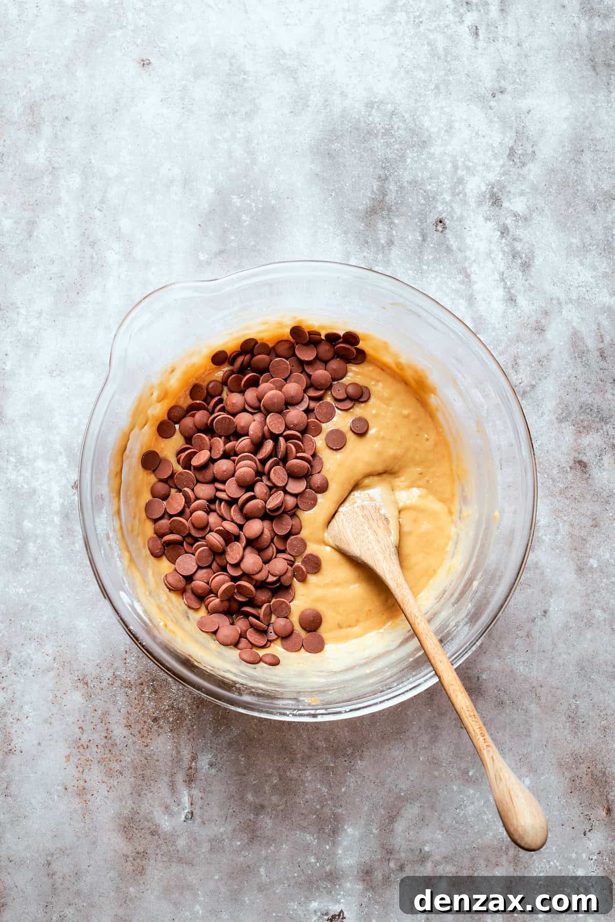 Semi-sweet chocolate chips being added to a bowl of banana bread batter.