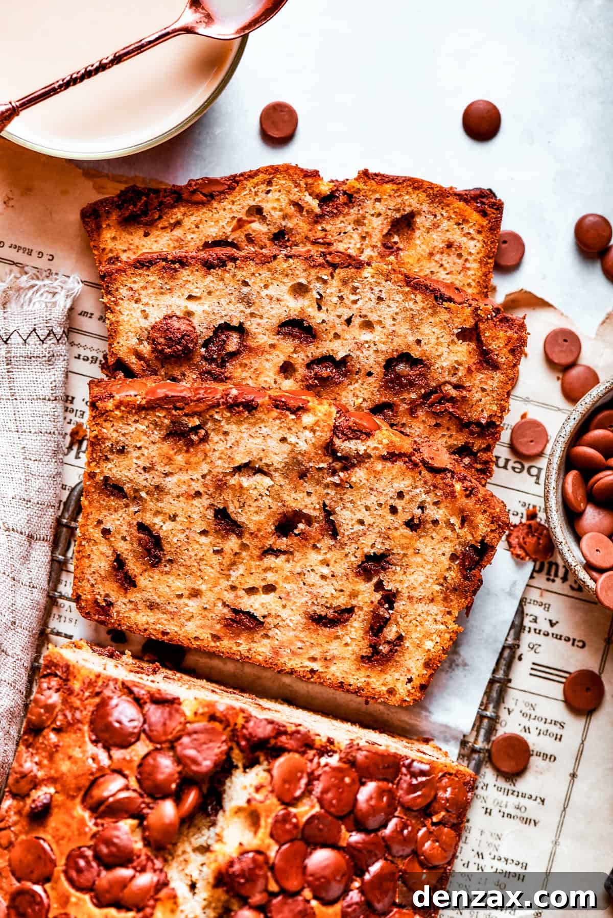 A beautifully sliced loaf of moist banana bread with visible chocolate chips on a cutting board.