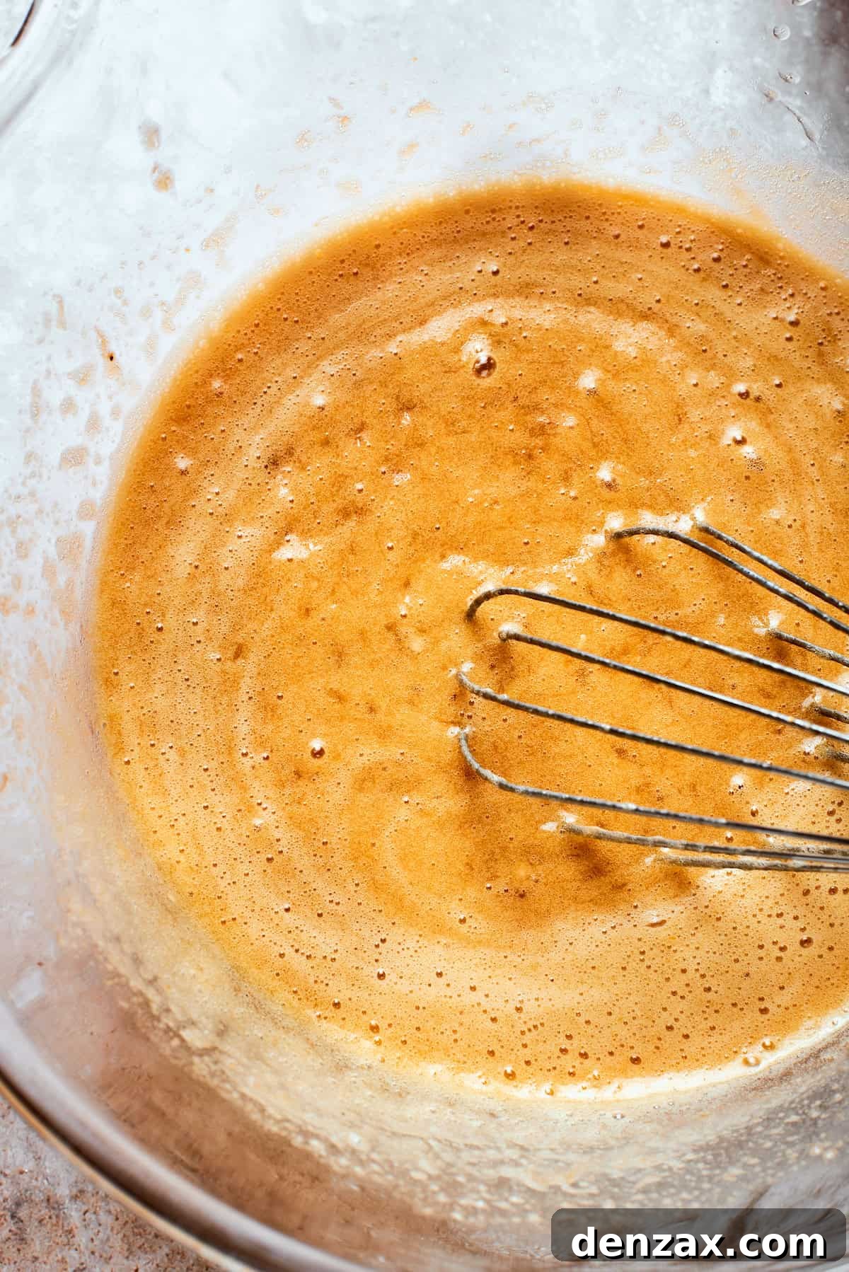 A whisk is used to thoroughly combine all the wet ingredients for a smooth banana bread batter.