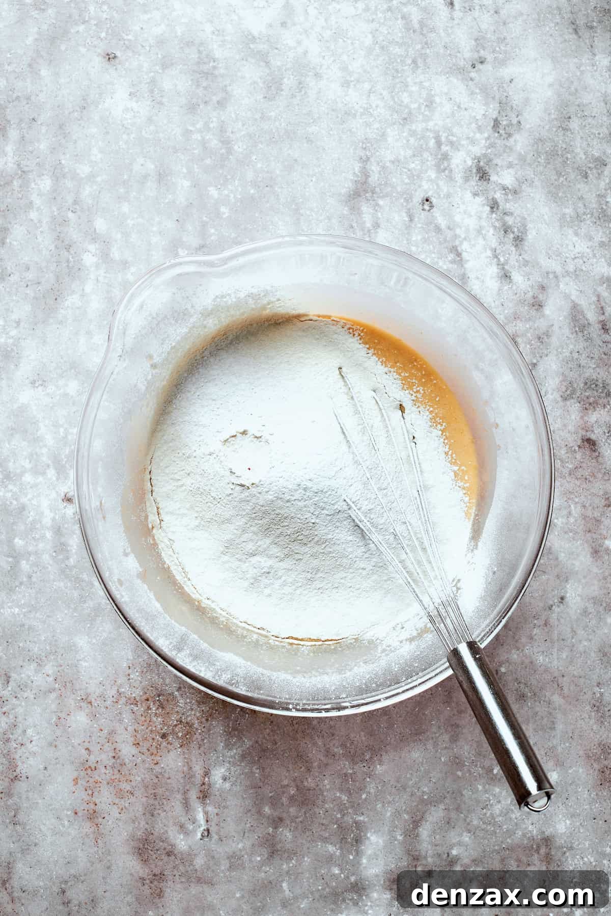 Dry ingredients, including flour, being mixed into the wet banana bread batter.