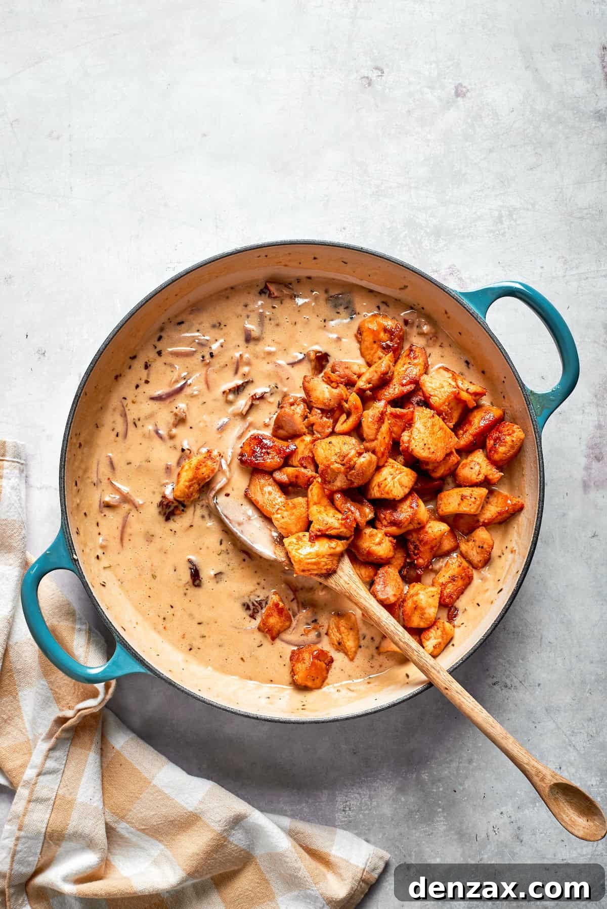 Cooked chicken added back to a skillet of cream sauce.